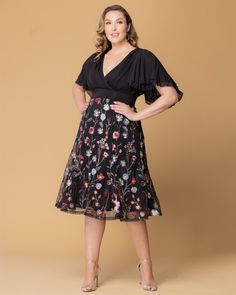 The Lillian Embroidered Cocktail Dress is a perfect choice for any special occasion. This plus size party dress features a black mesh bodice, surplice neckline, double layer flutter sleeves and a softly shirred waistband. The floral embroidered skirt includes godets for a touch of flirty movement. With its midi-length design, this dress is an elegant option for cocktail parties, as well as for the most stylish wedding guest or the mother of the bride/groom. This tea-length plus size mesh dress i Plus Size Party Dress, Jumpsuit And Cardigan, Embroidered Cocktail Dress, Plus Size Party, Chic Cardigan, Plus Size Party Dresses, Evening Gown Dresses, Surplice Neckline, Cocktail Parties