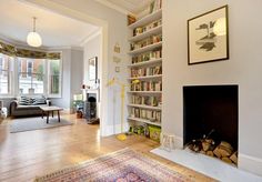 a living room filled with furniture and a fire place in front of a book shelf