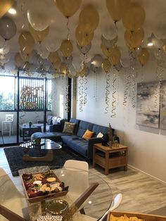 a living room filled with furniture and lots of balloons hanging from the ceiling above it