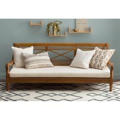 a wooden bench with pillows on it in front of a blue wall and shelfs