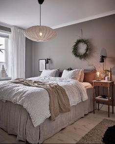 a bedroom with a large bed and two lamps hanging from the ceiling over it's headboard