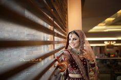 a woman in a red and gold bridal outfit standing next to a brick wall