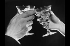 black and white photograph of two people toasting with wine glasses in front of them