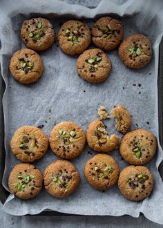 chocolate chip cookies with pistachios and almonds on a baking sheet, ready to be eaten