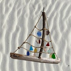 a small sailboat made out of wood and colored glass beads hanging from a rope