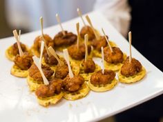 small appetizers with toothpicks in them on a white platter, ready to be served