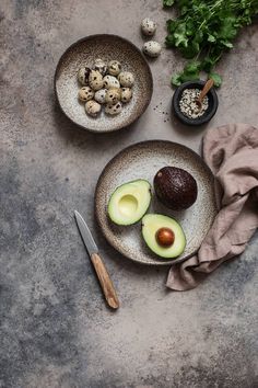 an avocado cut in half on a plate next to other fruits and vegetables