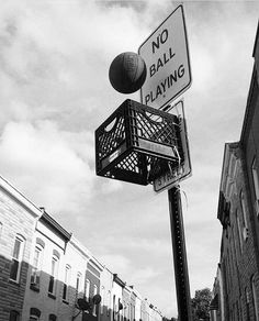 black and white photograph of a street sign with a ball in the basket on it