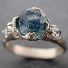 Partially faceted by my husband. blue Montana sapphire with conflict-free Fancy cut diamonds on each side. I hand carved this ring in wax and cast it in recycled solid 18k white gold using the lost wax casting process. This one of a kind gemstone ring is a size 7 and it can be resized. The sapphire stone measures about 7mm. The Fancy cut side diamonds are about 3mm (.285 side diamond tot ct wt.). The band is close to 3mm. Throughout all time and history, in every tribe and culture all around the Engagement Ring Blue Stone, Custom Gemstone Rings, Crystal Engagement Rings, Ocean Wedding, Blue Engagement Ring, Cute Engagement Rings, Women's Rings, Blue Stone Ring, Engagement Wedding Ring