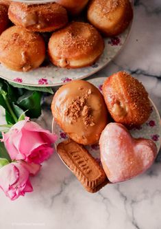 two plates filled with donuts next to pink flowers