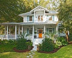 a white house with blue shutters on the front porch and steps leading up to it