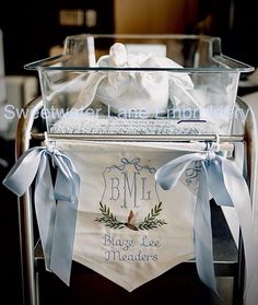 a clear basket filled with lots of white items on top of a metal cart covered in blue ribbon