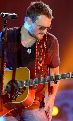 a man holding a guitar while standing in front of a microphone