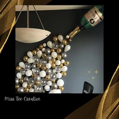 a bottle of champagne and some balloons on a black table with gold foil streamers