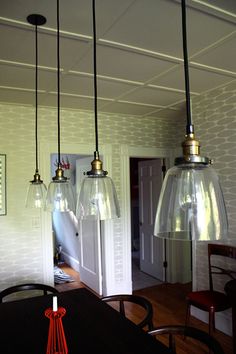 three lights hanging from the ceiling over a dining room table