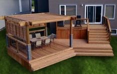 a wooden deck with chairs and stairs leading up to the back of a house on green grass