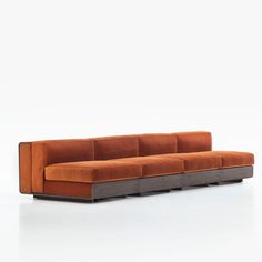 an orange and grey couch sitting on top of a white floor next to a wall