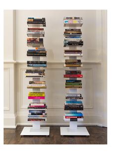 a tall stack of books sitting next to each other on top of white pedestals