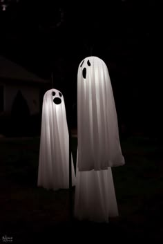 two white ghost statues standing in the dark