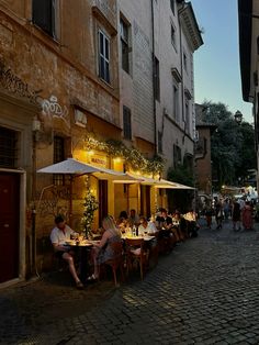 people are sitting at tables in an alleyway