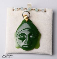 This Jade Buddha pendant stands out as a statement piece. The Sopel Sculpture to wear jewelry is embellished with Canadian Jade Precious Gemstone, 18KT Gold and a Rhodiated Silver Chain. Each unique piece is an original design and is fashioned by hand with precision in Vancouver, BC Canada at Studio Sopel. Registered and signed by renowned Jade Sculptor Lyle Sopel. These coveted bespoke signed original gem forms emulate the Museum caliber Sculpture Collections that have been Sopel Studio's insig Jade Pendant Amulet Jewelry, Jade Amulet Pendant Jewelry, Jade Cabochon Pendant Necklace, Unique Jade Pendant Jewelry, Antique Jade Pendant Necklace, Carved Pendant Jewelry For Formal Occasions, Art Deco Cabochon Pendant Jewelry, Formal Carved Pendant Jewelry, Collectible Jade Pendant Jewelry