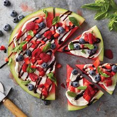 a pizza topped with berries and whipped cream on top of a green plate next to a spatula