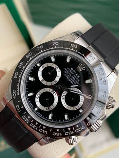 Die Rolex auf dem Bild ist eine Rolex Cosmograph Daytona.  Dieses Modell ist insbesondere am schwarzen Zifferblatt mit silbernen Hilfszifferblättern, der schwarzen Keramiklünette und dem Oysterflex-Armband zu erkennen, die bei einigen modernen Daytona-Referenzen wichtige Designelemente darstellen.
Aufgrund dieser Merkmale ist diese Rolex höchstwahrscheinlich aus der Oyster Perpetual Cosmograph Daytona 116519LN-Serie.  Die Referenznummer für dieses spezielle Modell wäre 116519LN, mit einer schwarzen Keramiklünette und einem schwarzen Zifferblatt mit einem Oysterflex-Armband. Classic Black Chronograph Watch With Subdials, Classic Black Watch Accessories With Tachymeter, Classic Black Chronograph Watch With Tachymeter, Luxury Black Chronograph Watch With Tachymeter, Classic Black Chronograph Watch With Chronometer, Timeless Black Chronograph Watch With Tachymeter, Luxury Black Watch Accessories With Analog Display, Luxury Black Chronometer Watch Accessories, Timeless Black Automatic Chronograph Watch