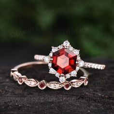 an engagement ring with a red stone surrounded by diamonds