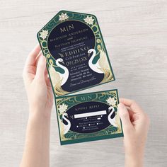 two hands holding up an elegant peacock wedding card