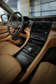 the interior of a modern car with tan leather and wood trims, including steering wheel