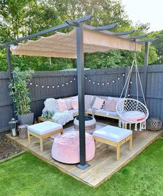 an outdoor area with furniture and pillows on the ground, in front of a wooden fence