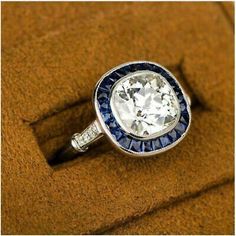 an antique style diamond and blue sapphire ring on a brown cloth with the words, i love