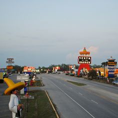 a woman with a large yellow hat standing on the side of a road