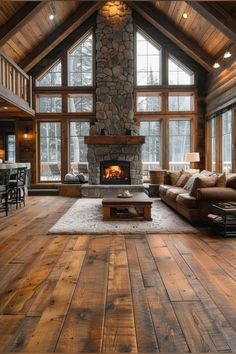 a living room filled with furniture and a fire place in the middle of a wooden floor