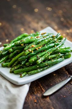 a white plate topped with green beans covered in seasoning and sprinkles