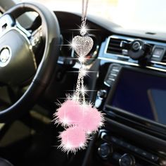 a car dashboard with a pink heart hanging from it's center console