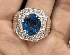 a ring with a blue stone surrounded by white and brown diamonds on it's finger