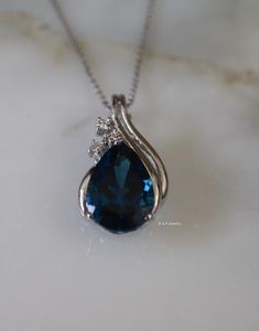 Metal: 14kt White Gold Stone: Diamond And Swiss Blue Topaz Shape: Round And Pear-Shape Blue Topaz Weight: 6.00 ctw Blue Topaz Size: 14 x 9mm Diamond Weight: .10 ctw Weight Of Pendant And Chain: 6.10 grams Length Of Pendant With Bail From Top To Bottom: 27 mm Type of chain: 14kt White Gold 1mm Diamond Cut Curb Chain Pendant Type: Enhancer Pendant Length of chain: 16 Inches Customizable: We can make this pendant in any metal, with any gem types. Please inquire if interested. Note: Other chain styl Blue Topaz Pendant Jewelry For Wedding, Blue Pear-shaped Diamond Necklace, Blue Pear-shaped Topaz Jewelry, Blue Pear-shaped Blue Topaz Necklace, Pear-shaped Blue Topaz Gemstone Jewelry, Blue Gem Necklace, Diamond Enhancer, Puzzle Jewelry, Diamond Pendants Designs