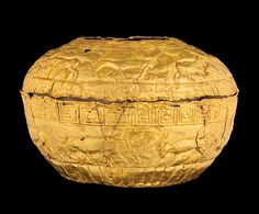 an old gold vase with carvings on it