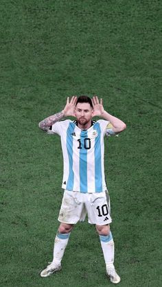 a man standing on top of a soccer field holding his hands up