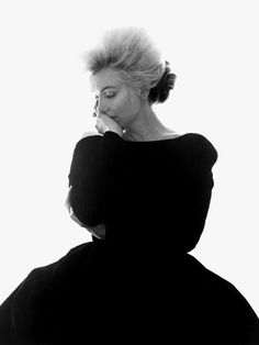 a black and white photo of a woman with her hair in a bun looking down