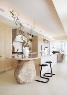 a kitchen with a large rock in the center and two stools next to it