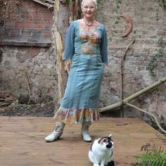 a woman standing next to a black and white cat