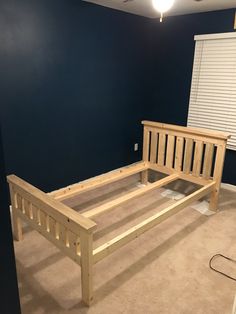 a bed frame in the middle of a room with blue walls and tan carpeting