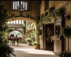 two horses are walking through an archway in a building with potted plants on either side