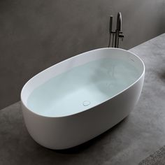 a white bath tub sitting on top of a bathroom counter next to a faucet