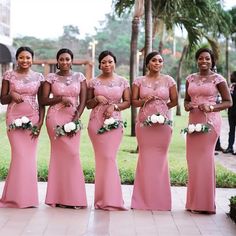 a group of women standing next to each other wearing pink dresses and holding bouquets