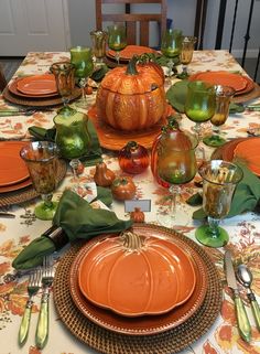 the table is set for thanksgiving dinner with orange plates and pumpkins on top of them