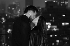 a man and woman kissing in front of the city lights