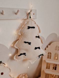 a white christmas tree hanging from the side of a wall next to a doll house